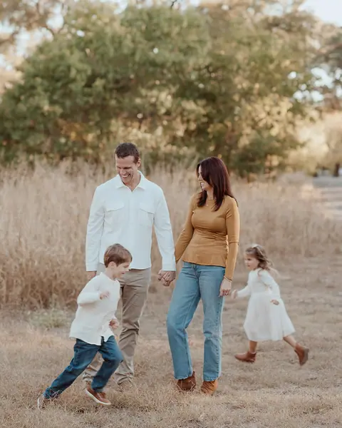The Hogenson family outdoors: Daniel Hogenson, Lauren and two young children walking through tall grass