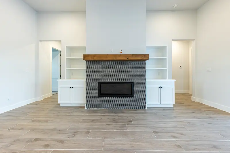 Fireplace with a wood mantel between white built-in cabinets, Farmhouse Hill Country Retreat (RenovatePros project)