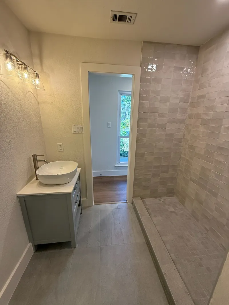 Bathroom with a vessel sink vanity and a tiled walk-in shower, Oak Hill-area remodel by RenovatePros