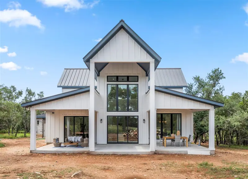 Back of the home: a tall gabled glass wall over the covered patio, Round Mountain Modern Farmhouse (RenovatePros project)