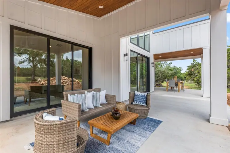 Covered back patio with a wood ceiling, glass doors and outdoor seating, Round Mountain Modern Farmhouse (RenovatePros project)