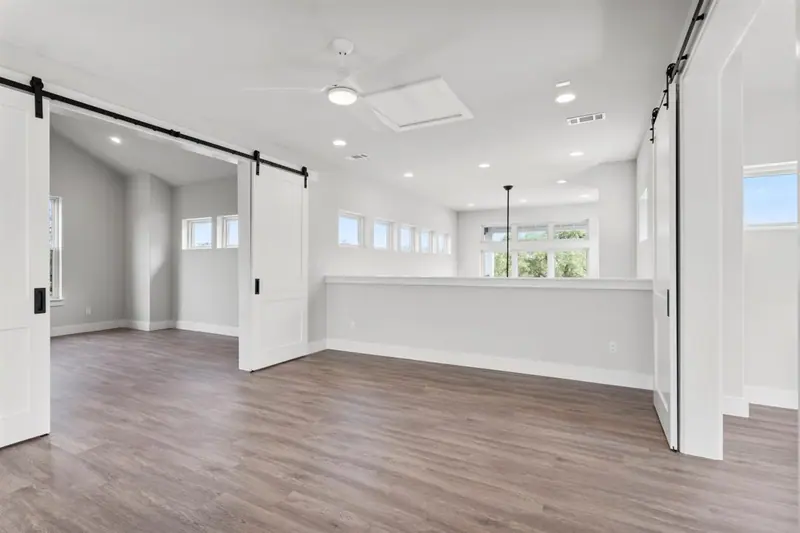 Upstairs room with wood-look floors and sliding barn doors, Round Mountain Modern Farmhouse (RenovatePros project)