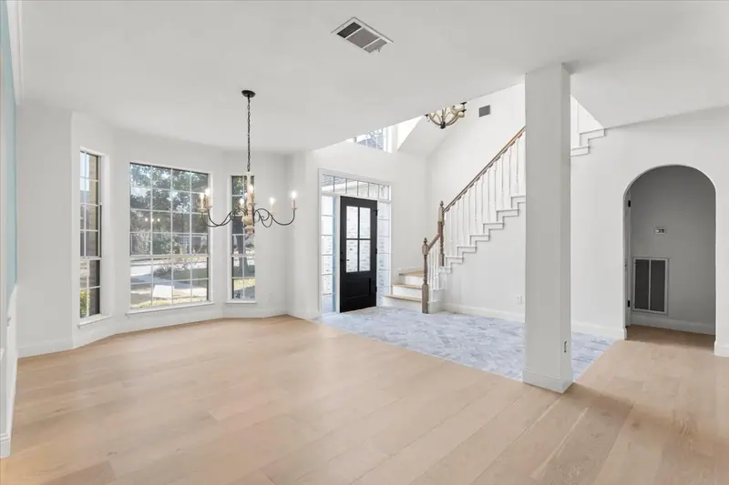 Entry hall with a brick floor, a staircase with white balusters and a chandelier, Round Rock French Country Remodel (RenovatePros project)