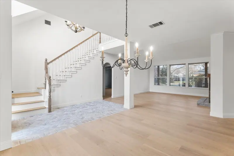 Staircase and brick-floored entry opening to the main living area, Round Rock French Country Remodel (RenovatePros project)