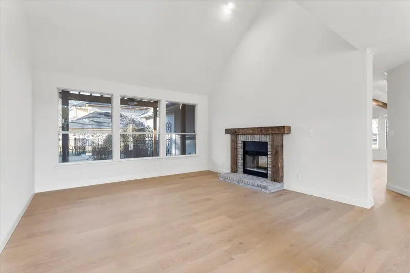 Living room with a brick fireplace, a rough wood mantel and a wide window, Round Rock French Country Remodel (RenovatePros project)