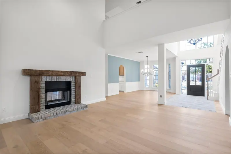 Brick fireplace with a wood mantel, looking toward the front entry, Round Rock French Country Remodel (RenovatePros project)