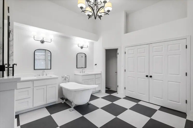 Primary bathroom with a black and white checkerboard floor, a clawfoot tub and two vanities, Round Rock French Country Remodel (RenovatePros project)