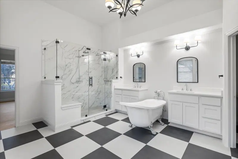 Primary bathroom with a glass walk-in shower, clawfoot tub and checkerboard floor, Round Rock French Country Remodel (RenovatePros project)