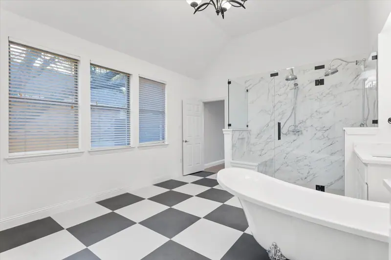Clawfoot tub under a row of windows, with the glass shower behind it, Round Rock French Country Remodel (RenovatePros project)