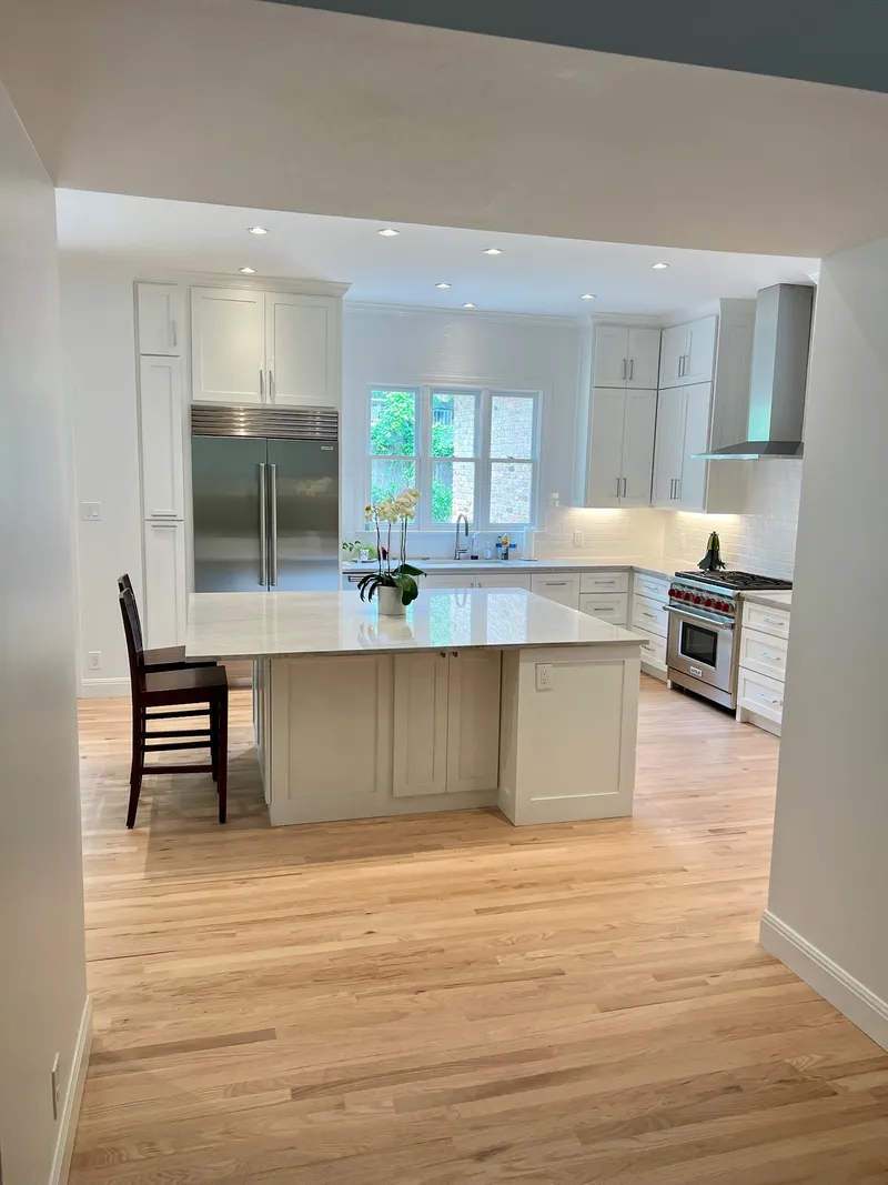 Open kitchen with white cabinets, a stainless range and a large island, Westlake-area remodel by RenovatePros
