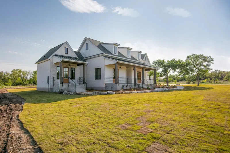 Side of the home across a new lawn, Spicewood Modern Farmhouse (RenovatePros project)