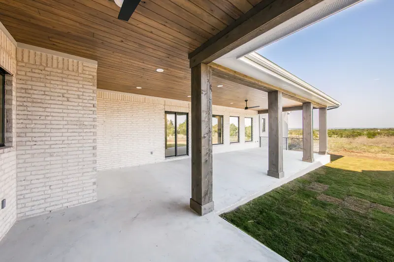 Covered back patio with a wood ceiling and wood posts, Spicewood Modern Farmhouse (RenovatePros project)