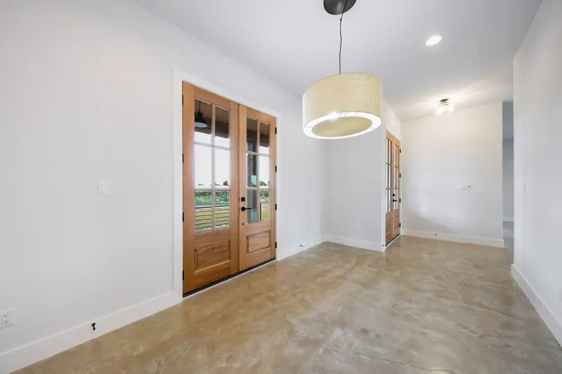 Dining area with wood double doors and a drum pendant light, Spicewood Modern Farmhouse (RenovatePros project)
