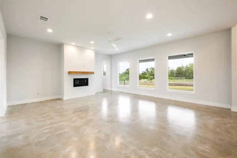 Living room with a fireplace, a wood mantel and three windows, Spicewood Modern Farmhouse (RenovatePros project)