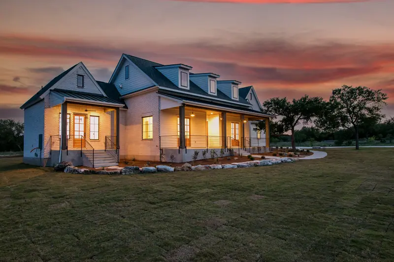 Front porch at dusk, seen from the corner, with the lights on, Spicewood Modern Farmhouse (RenovatePros project)