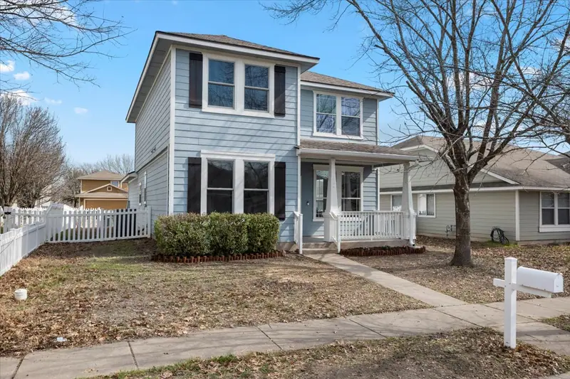 Front of the two-story home: blue siding, a white front porch and a picket fence, Two-Story Home Remodel, 2026 (RenovatePros project)