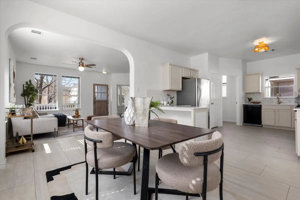 Open kitchen, dining and living area with an arched opening and light tile floors, Two-Story Home Remodel, 2026 by RenovatePros
