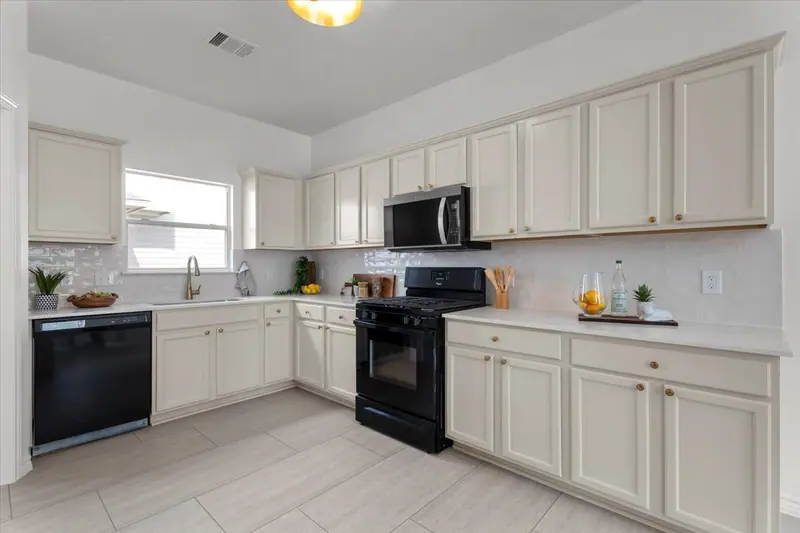 Kitchen with cream cabinets, white counters, a tile backsplash and black appliances, Two-Story Home Remodel, 2026 (RenovatePros project)