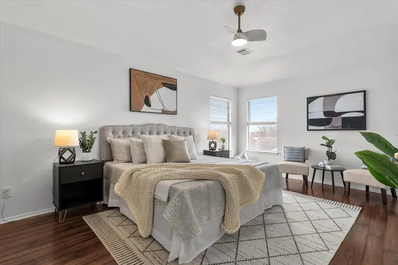 Primary bedroom with a tufted bed, two windows and a sitting area, Two-Story Home Remodel, 2026 (RenovatePros project)