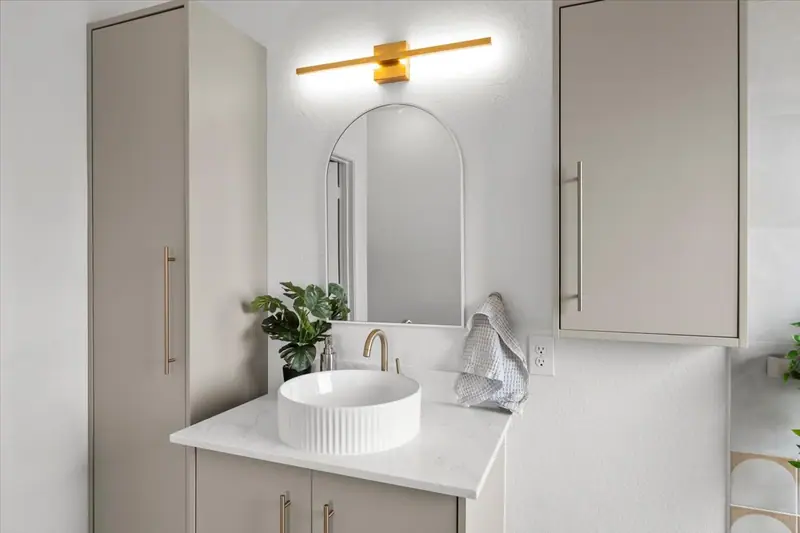 Floating vanity with a vessel sink, arched mirror and gold light bar, Two-Story Home Remodel, 2026 (RenovatePros project)