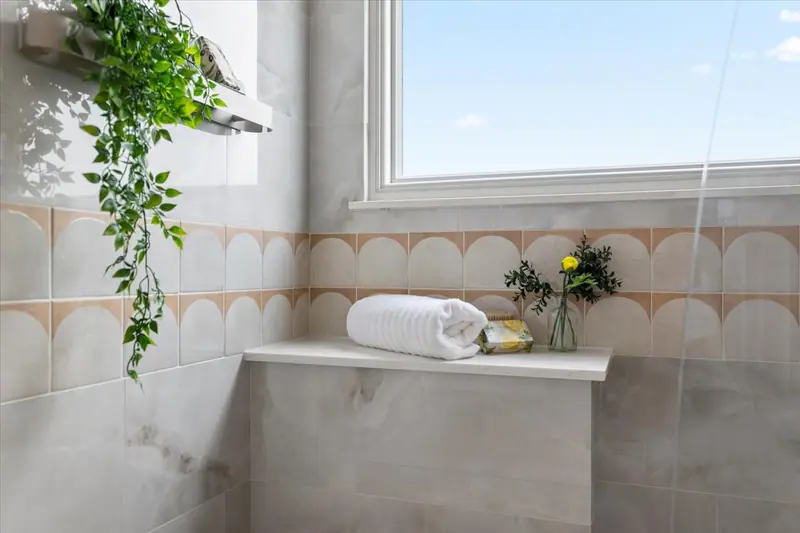 Shower bench with marble-look tile under a window, Two-Story Home Remodel, 2026 (RenovatePros project)